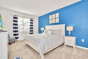 A bedroom with a bed, bedside tables, curtains, and wall art. - Waterfront Family Mansion w BBQ, Games Room & Pool (Kissimmee)