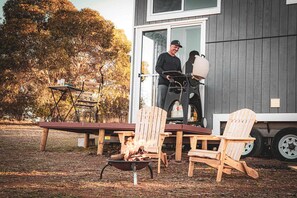 A deck with outdoor seating, a fire pit, and a building with a sliding door.