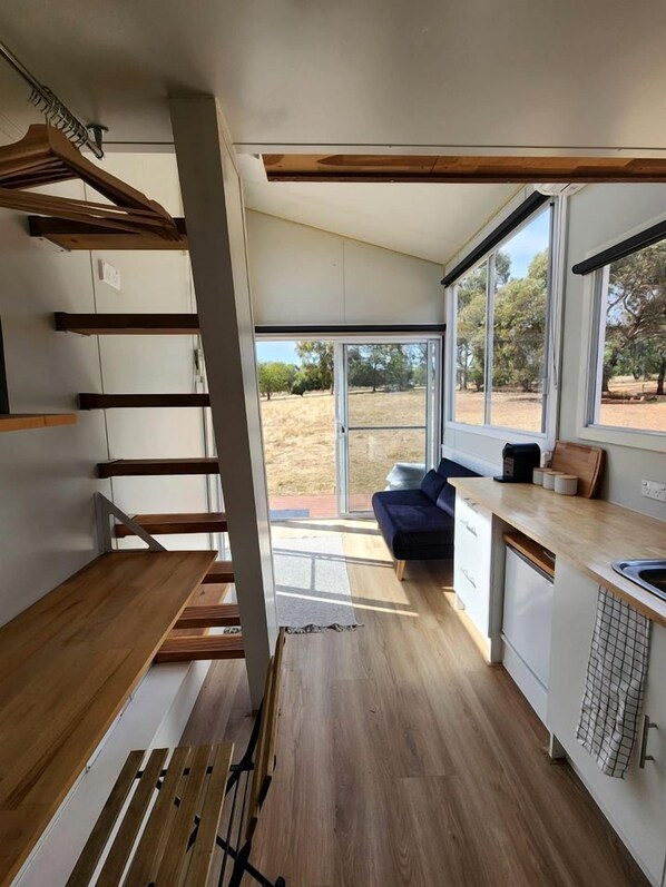 A modern kitchen with wooden flooring, a built-in bench, and large windows offering a view of the outdoors.