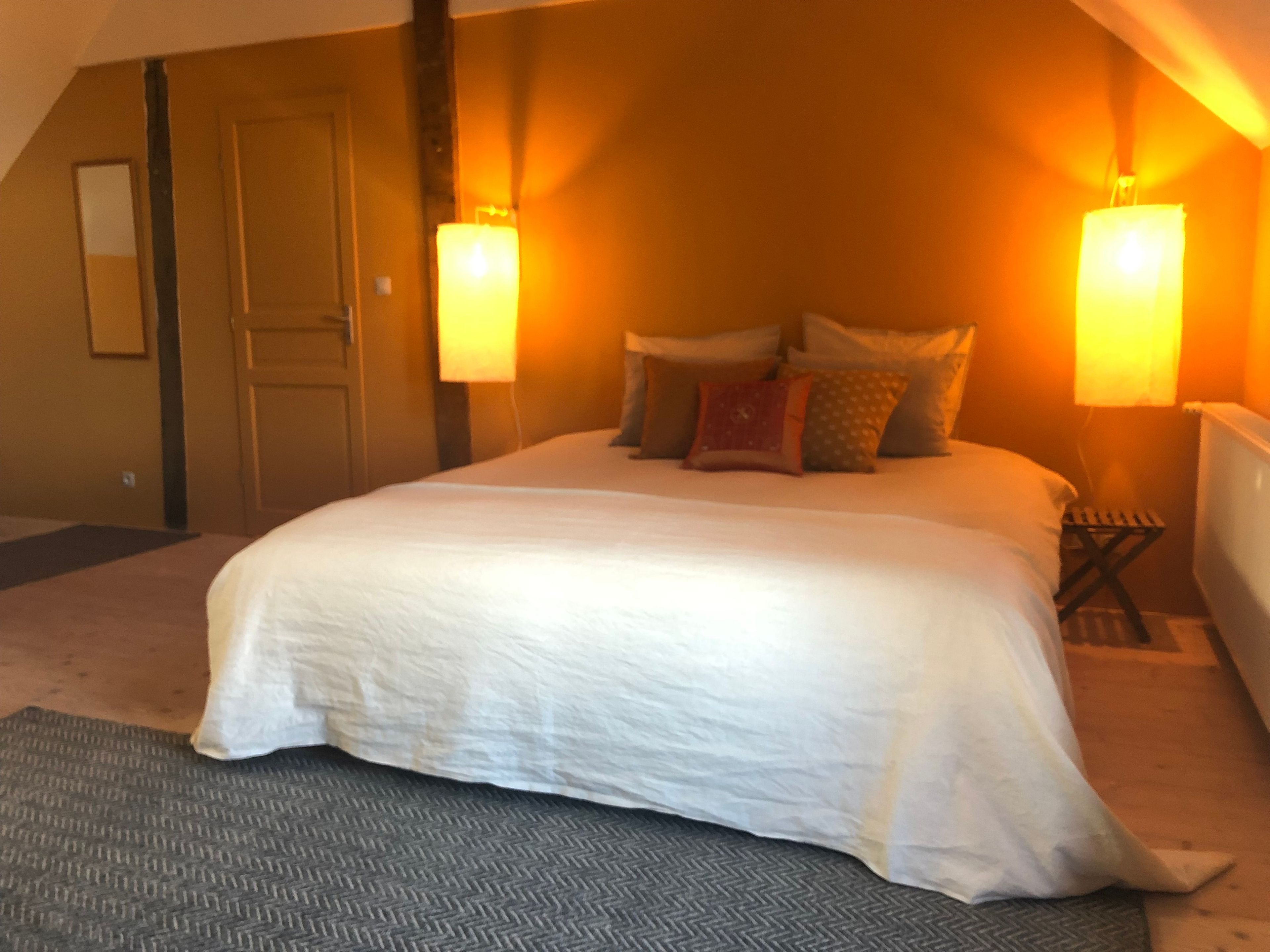 Een slaapkamer met een groot bed, twee bedlampen, een nachtkastje en een deur.