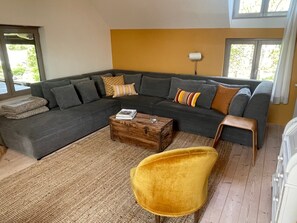 A modern living room with a sectional sofa, a wooden coffee table, and a yellow armchair.