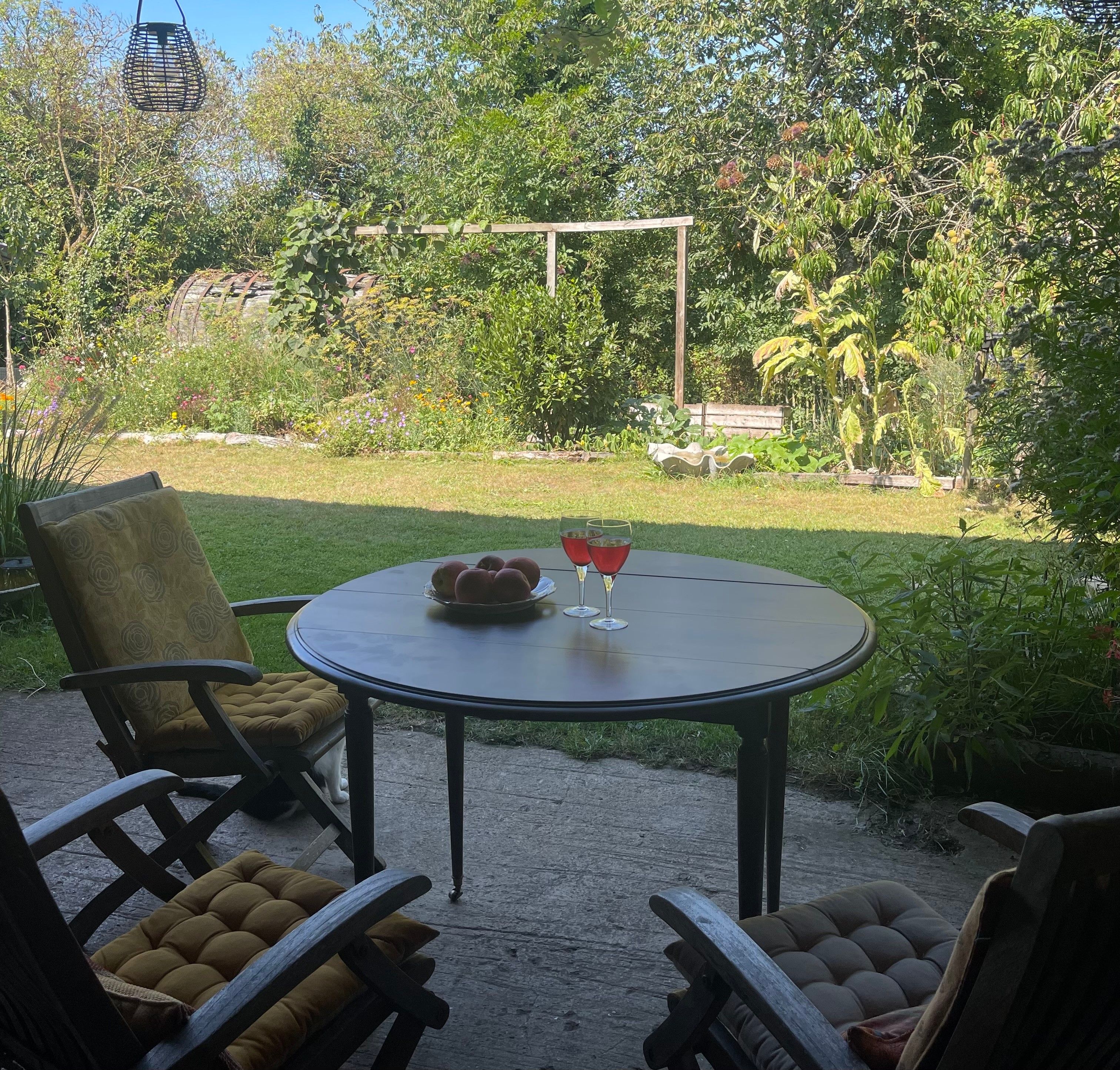Een terras buiten met een ronde tafel, twee stoelen en een decoratieve schaal.