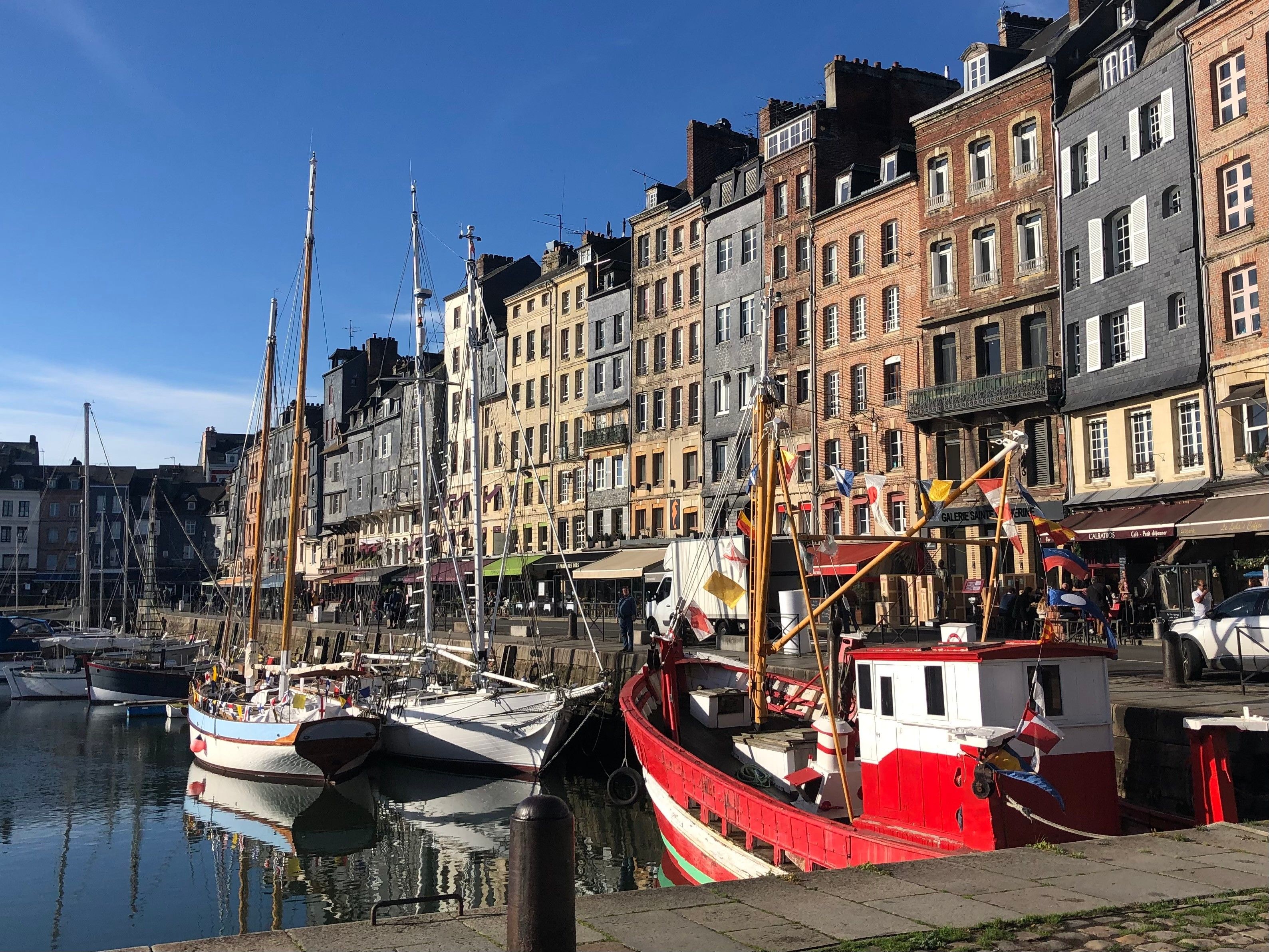 Ein Ufer mit bunten Gebäuden, eine Anlegestelle mit Booten und ein klarer Himmel.