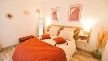 A bedroom with a bed, bedside tables, a nightstand, a mirror, and wall decorations.