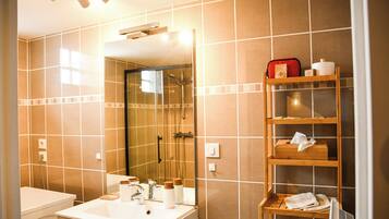 A bathroom with a white sink, mirror, and a wooden shelf with toiletries.