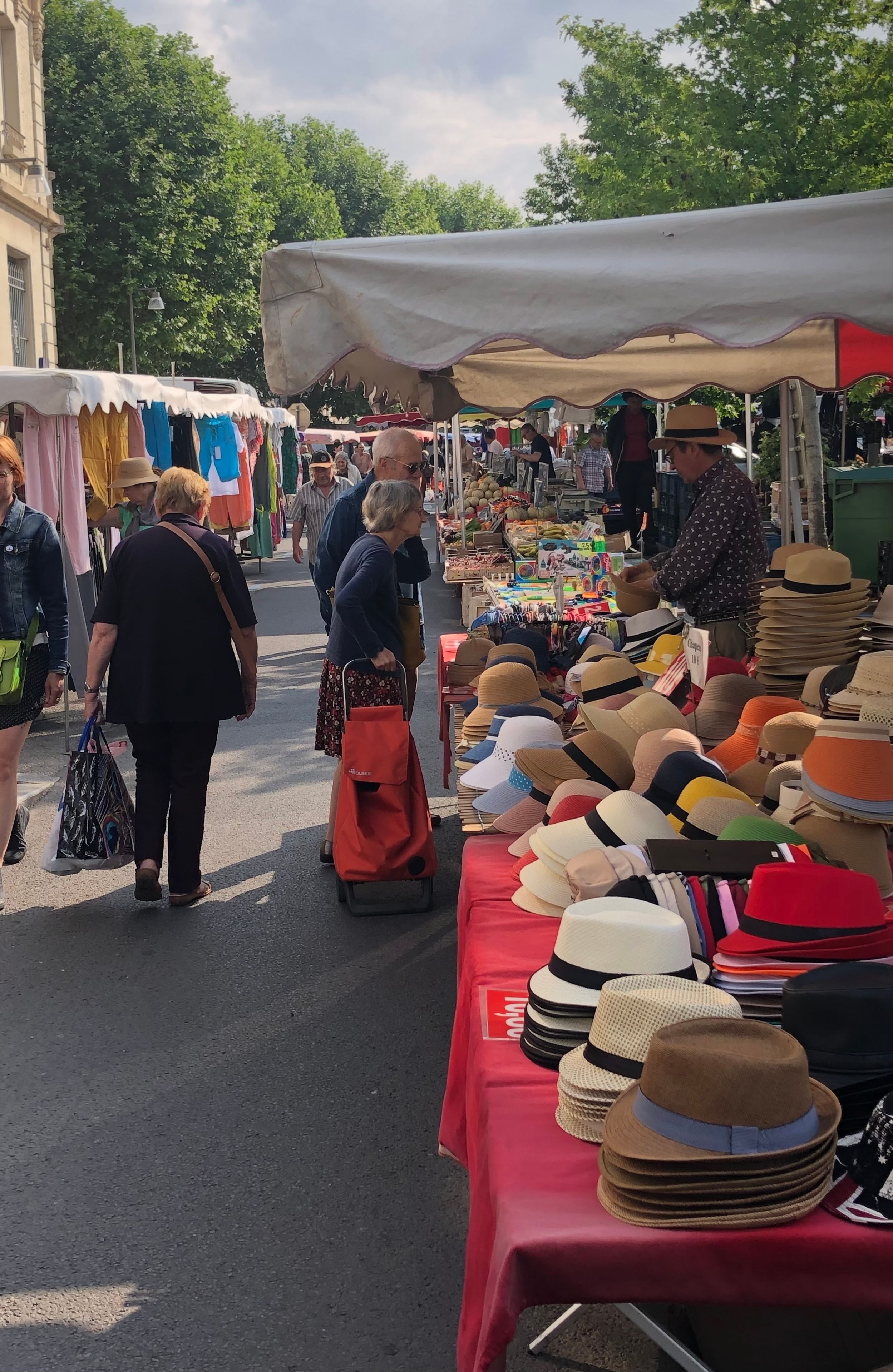 Een markt met verschillende kraampjes, waaronder een met hoeden.