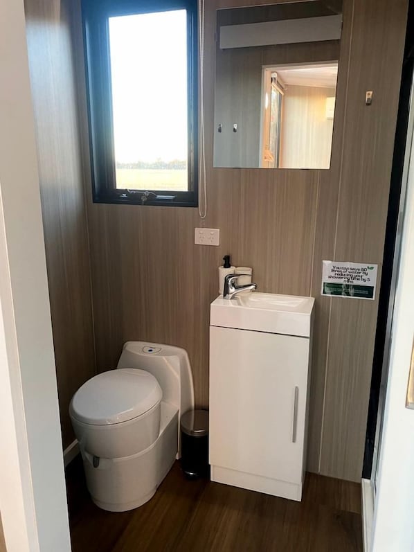 A compact bathroom with a toilet, sink, and storage cabinet.