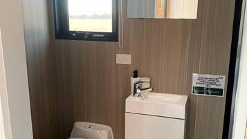 A compact bathroom with a toilet, sink, and storage cabinet.