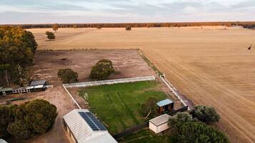 A large open field with a fenced area, a building with solar panels, and a small structure.