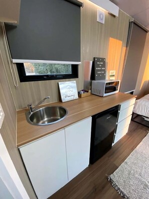 A compact kitchen with a sink, microwave, and a sign that reads 'Welcome to Farm Stay.' - Tiny House Stay with Cozy Fireplace and Nature Views in Koonoomoo, Australia (Koonoomoo)