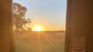 A doorway leading to a grassy outdoor area with a view of the sunset.
