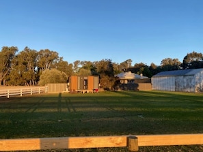 A fenced outdoor area with a building, a shed, and trees.