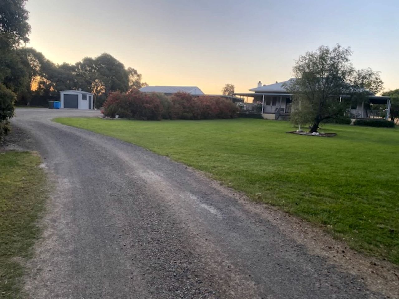 A gravel driveway leading to a house with a garage and a covered porch.