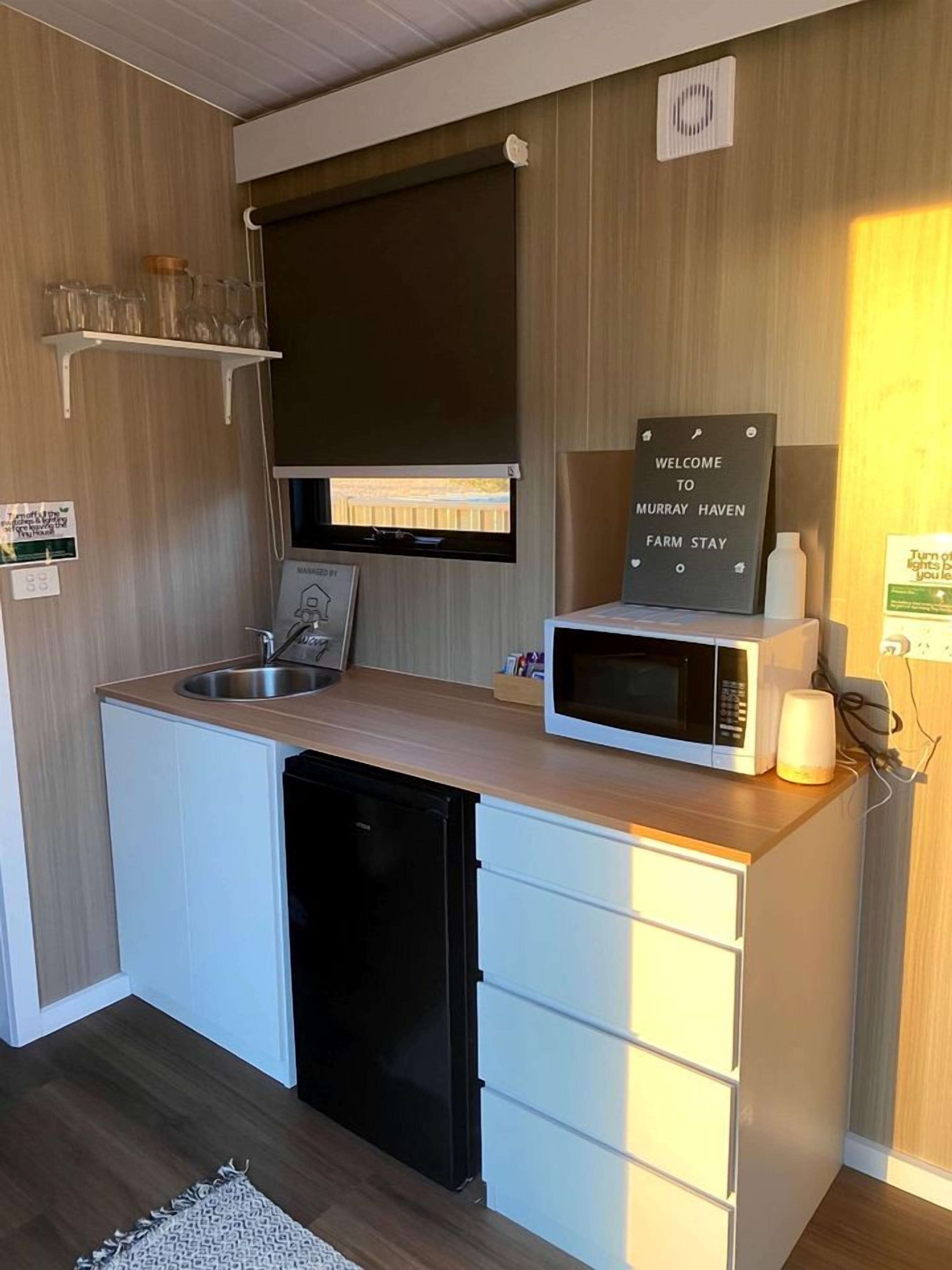 Una kitchenette compacta con microondas, pileta y un cartel que dice 'WELCOME TO MURRAY HAVEN FARM STAY'.