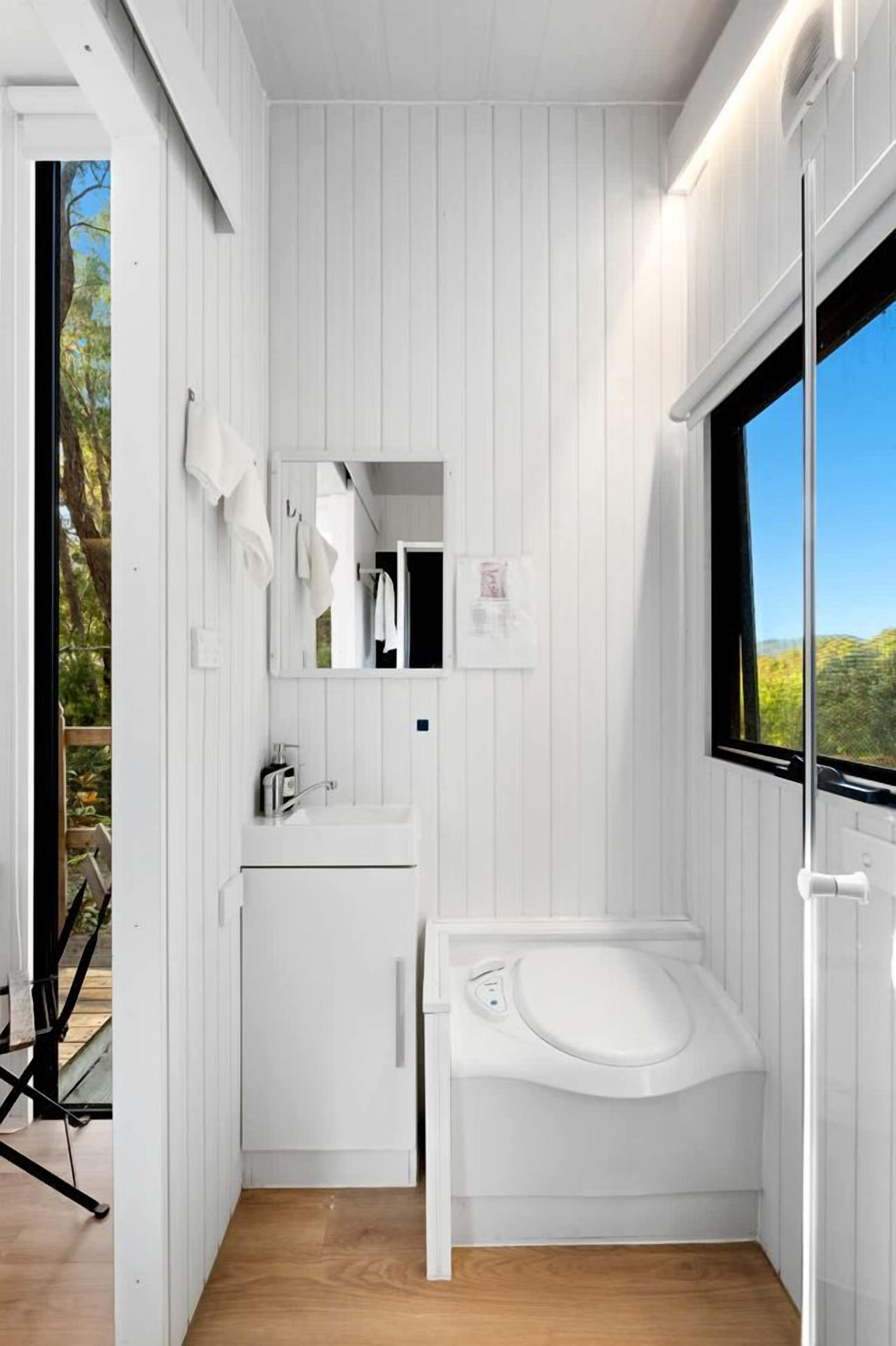 A compact bathroom with a white sink, a mirror, and a toilet.