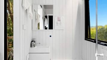 A compact bathroom with a white sink, a mirror, and a toilet.
