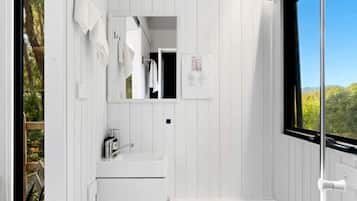 A compact bathroom with a white sink, a mirror, and a toilet.
