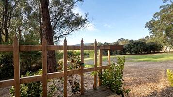 A wooden deck with a view of a grassy area and trees.