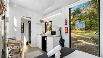Un dormitorio moderno con una cama grande, una kitchenette pequeña y vistas al exterior.