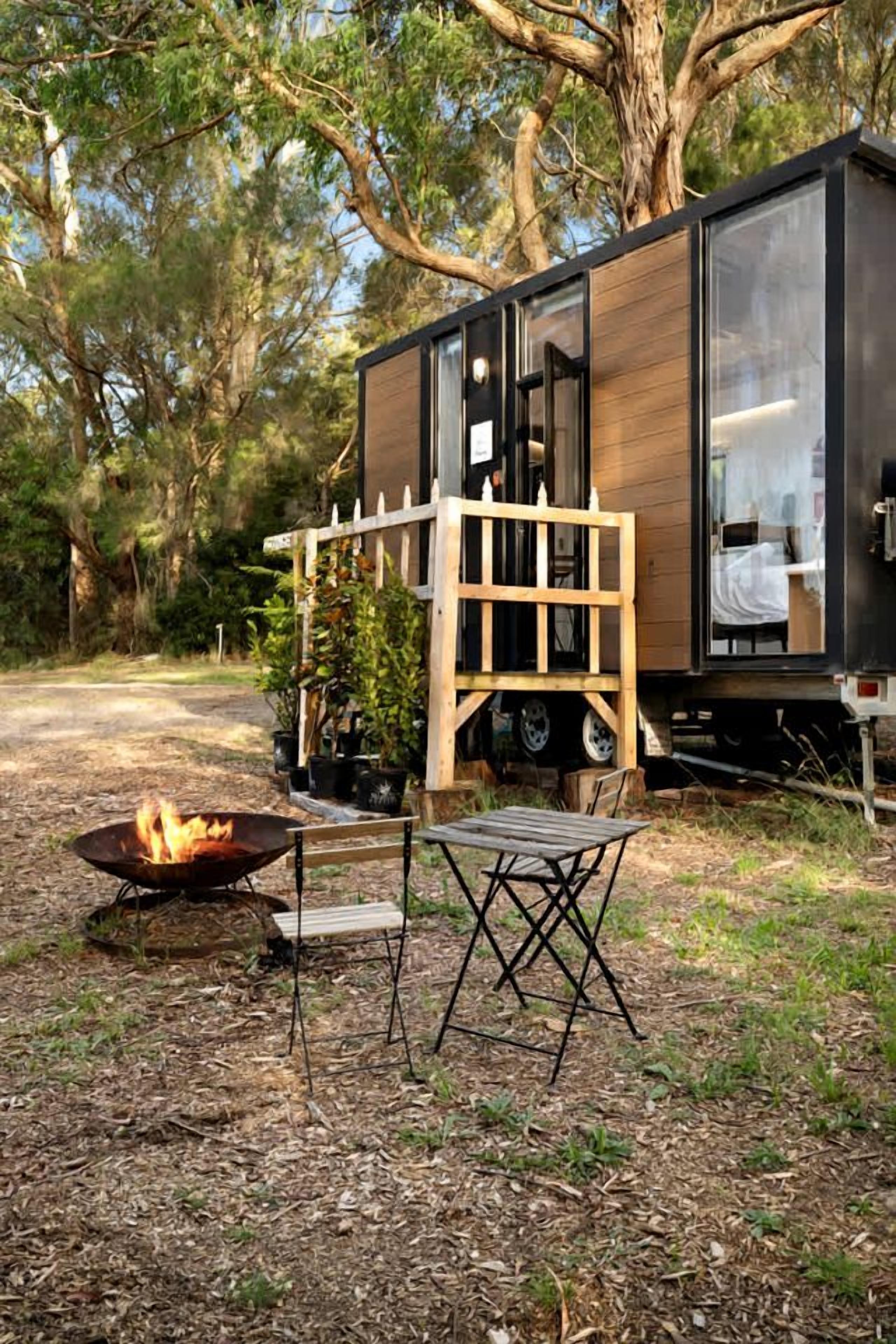 Eine moderne Blockhütte mit einer Terrasse, einer Feuerstelle und einem Tisch.