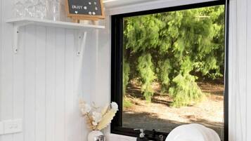 A kitchen with a built-in dishwasher, a sink, and a window displaying a forest scene.