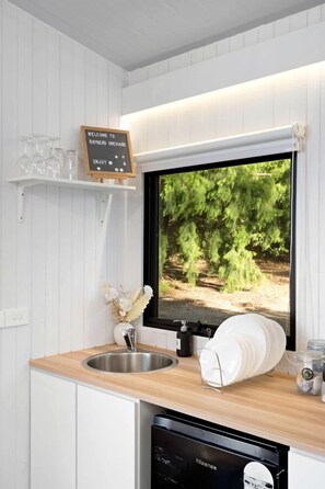 Una cocina con lavavajillas integrado, un lavabo y un ventanal que muestra un paisaje boscoso.