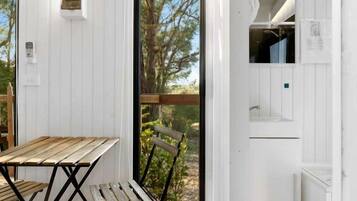 A room with a wooden table and chairs, a white wall with a window, and a view of trees.