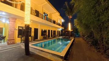 A hotel with a swimming pool, multiple balconies, and a well-lit exterior.