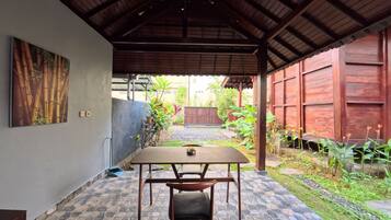 An outdoor covered patio with a table and chairs, a tiled floor, and a wooden ceiling.