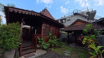 A traditional wooden house with a tiled roof, a porch, and a garden with gravel paths.