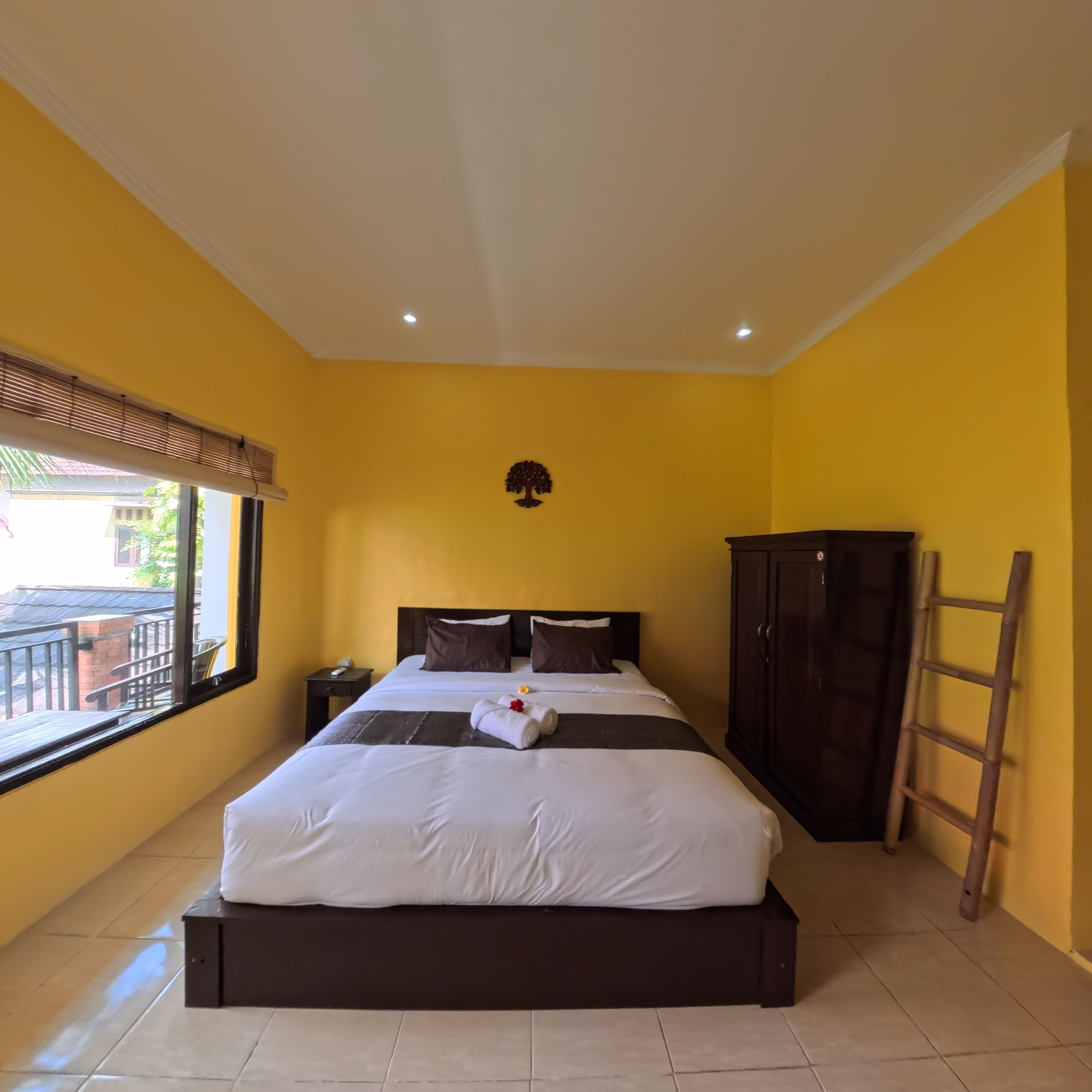 Una habitación de hotel con cama, mesita de noche, armario y ventana con vistas.