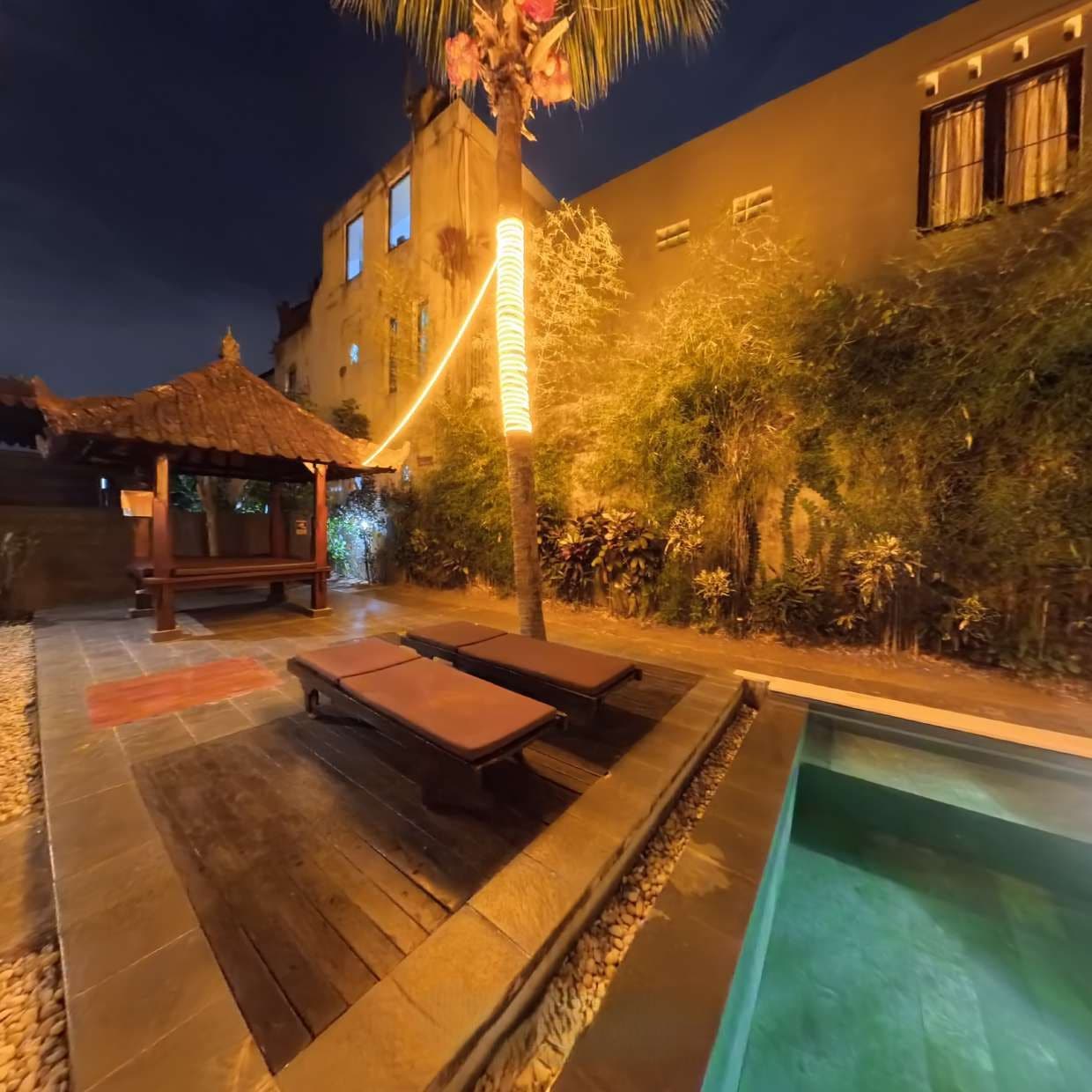 An outdoor pool area with lounge chairs and a small gazebo.