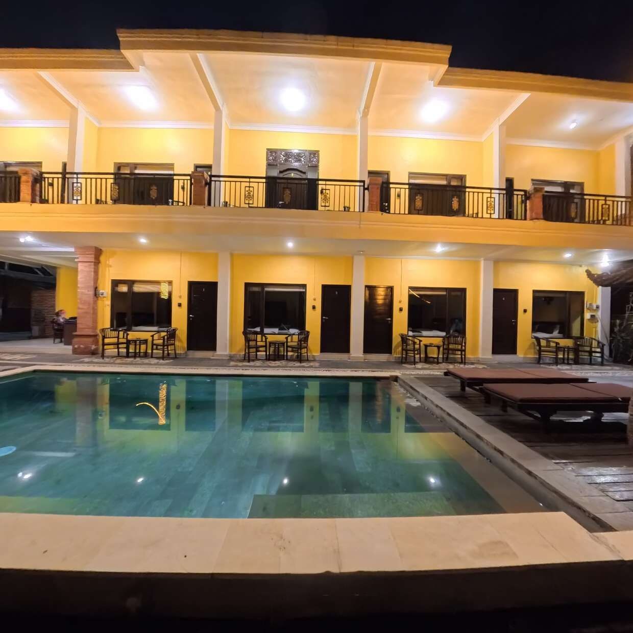 A hotel with a pool, outdoor seating, and a two-story structure.