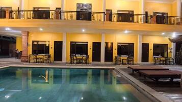 A hotel with a pool, outdoor seating, and a two-story structure.