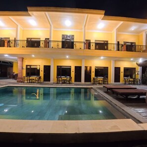 Un hotel con piscina, asientos al aire libre y una estructura de dos pisos.