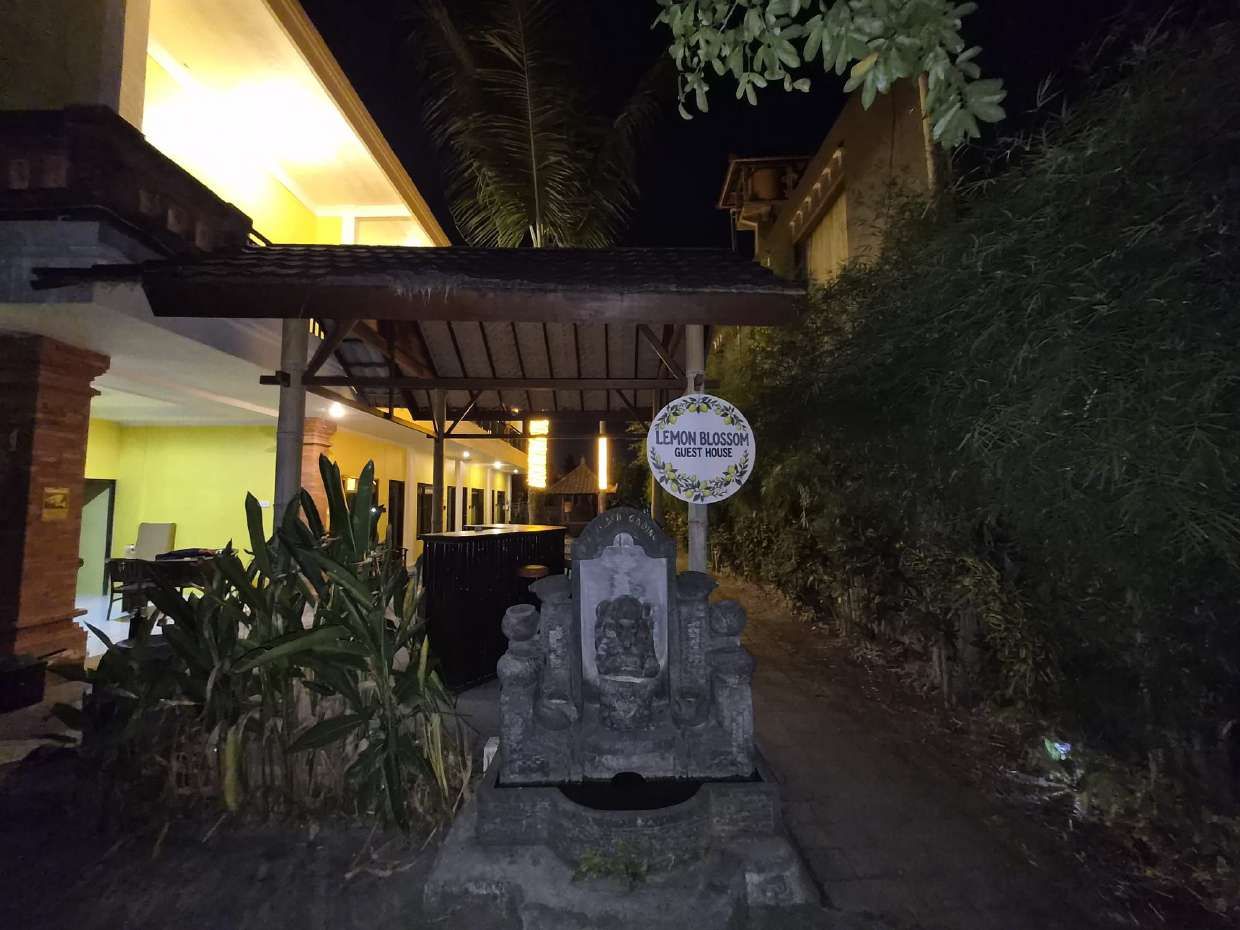 L'ingresso di una pensione, con un cartello, una struttura in pietra e un edificio sullo sfondo.