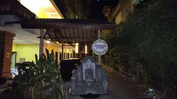 L'ingresso di una pensione, con un cartello, una struttura in pietra e un edificio sullo sfondo.