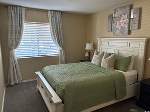 A bedroom with a bed, curtains, a nightstand, a lamp, and wall art. - Desert Magnolia | Cozy 1BR Sedona Retreat | Sleeps 4 (Sedona)