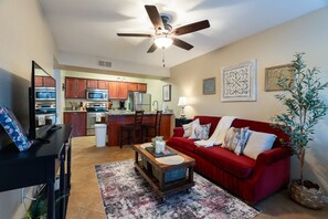 A living room with a red sofa, a coffee table, and a ceiling fan. - Desert Magnolia | Cozy 1BR Sedona Retreat | Sleeps 4 (Sedona)
