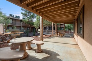 Ein Außenbereich mit Terrasse, einem Pergola, Steintischen und Bänken.
