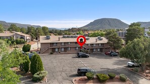 A multi-story hotel with a parking lot, surrounded by trees and a mountain in the background. - Desert Magnolia | Cozy 1BR Sedona Retreat | Sleeps 4 (Sedona)