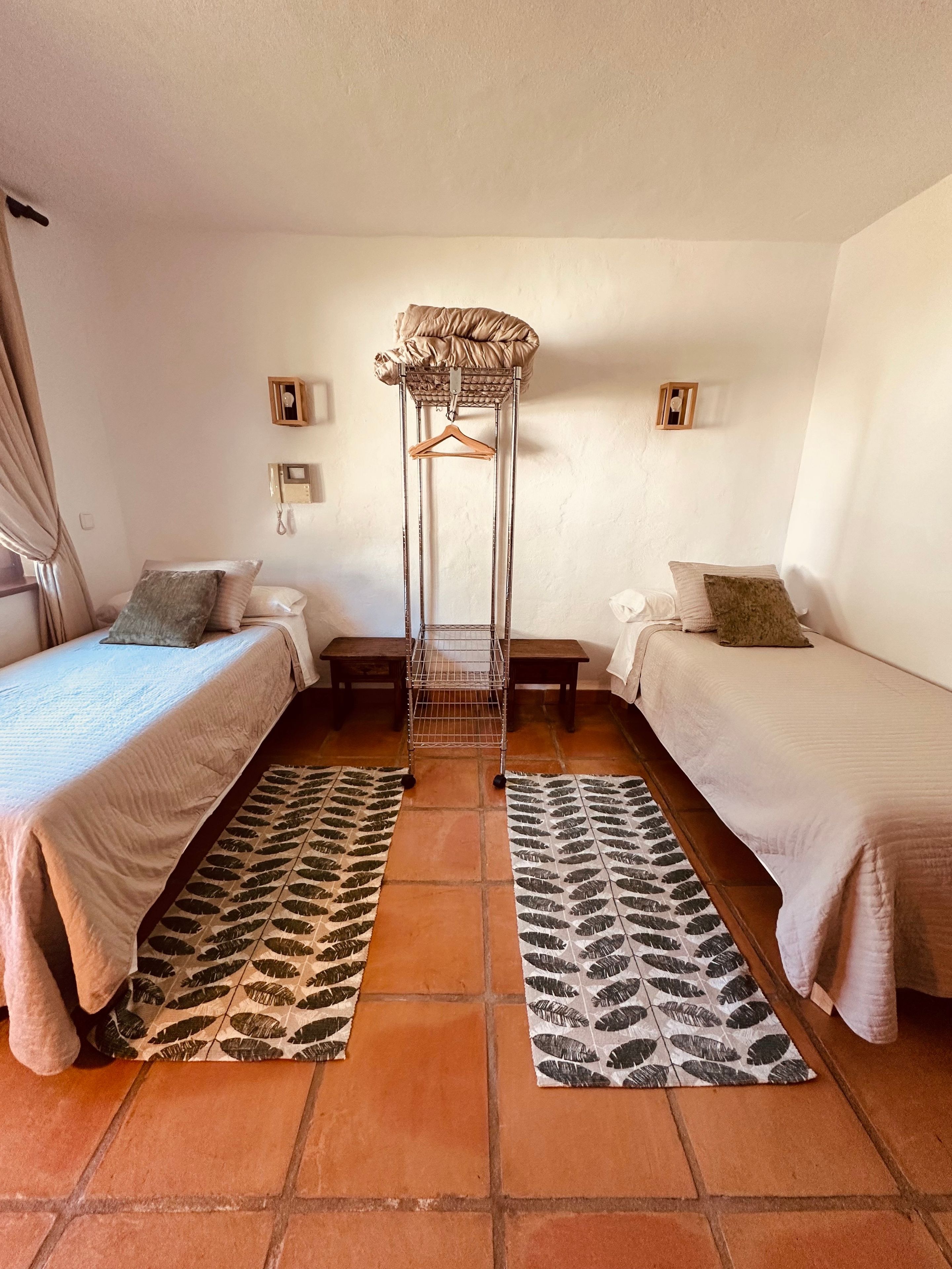 A room with two beds, a hanging chair, and a patterned rug.