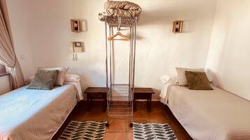 A room with two beds, a hanging chair, and a patterned rug.