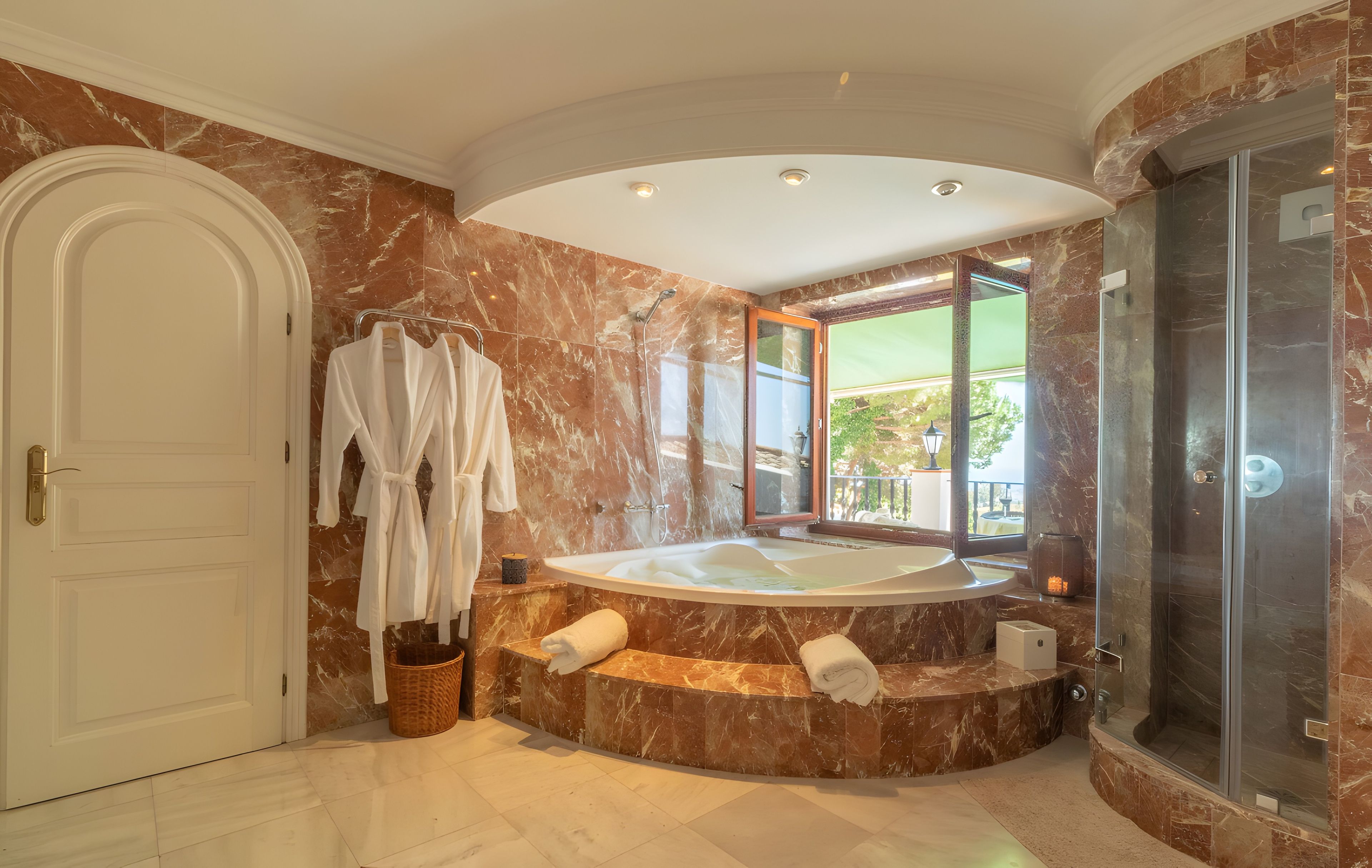 A luxurious bathroom with a marble floor, a large bathtub, and a glass-enclosed shower.