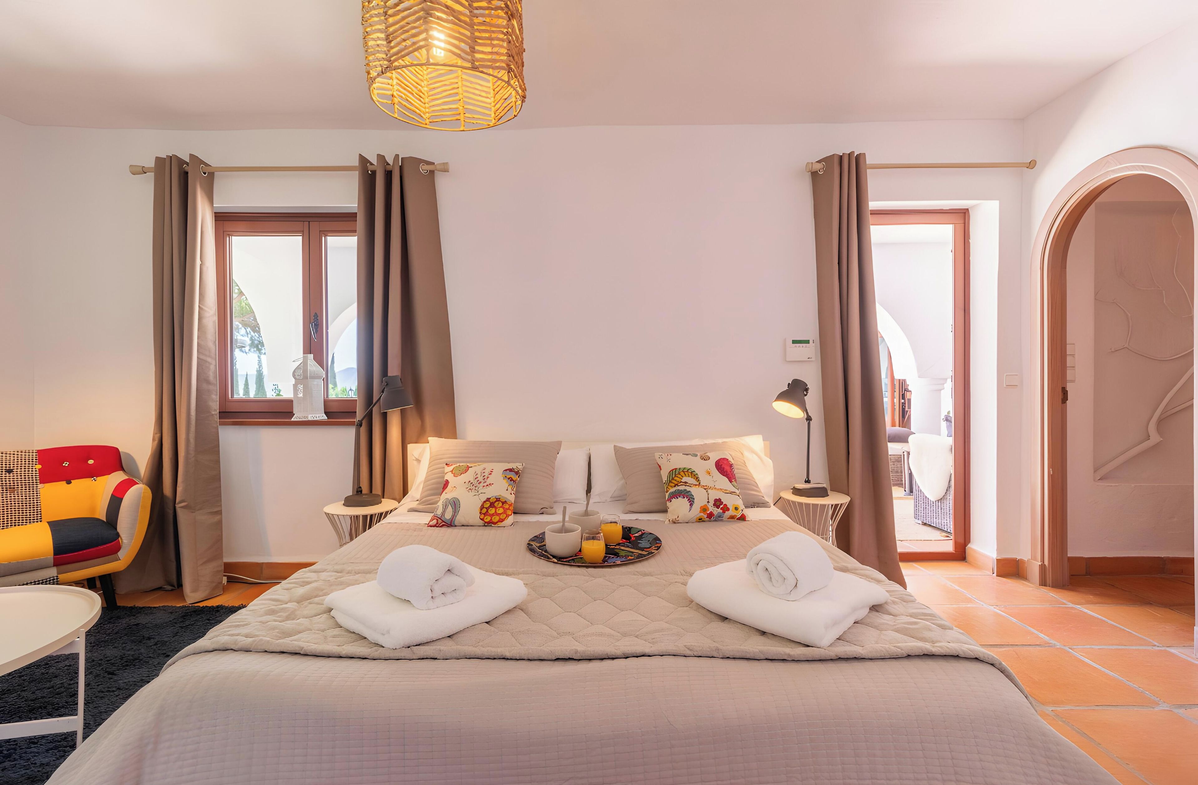Een hotelkamer met een bed, nachtkastjes, een stoel en uitzicht.
