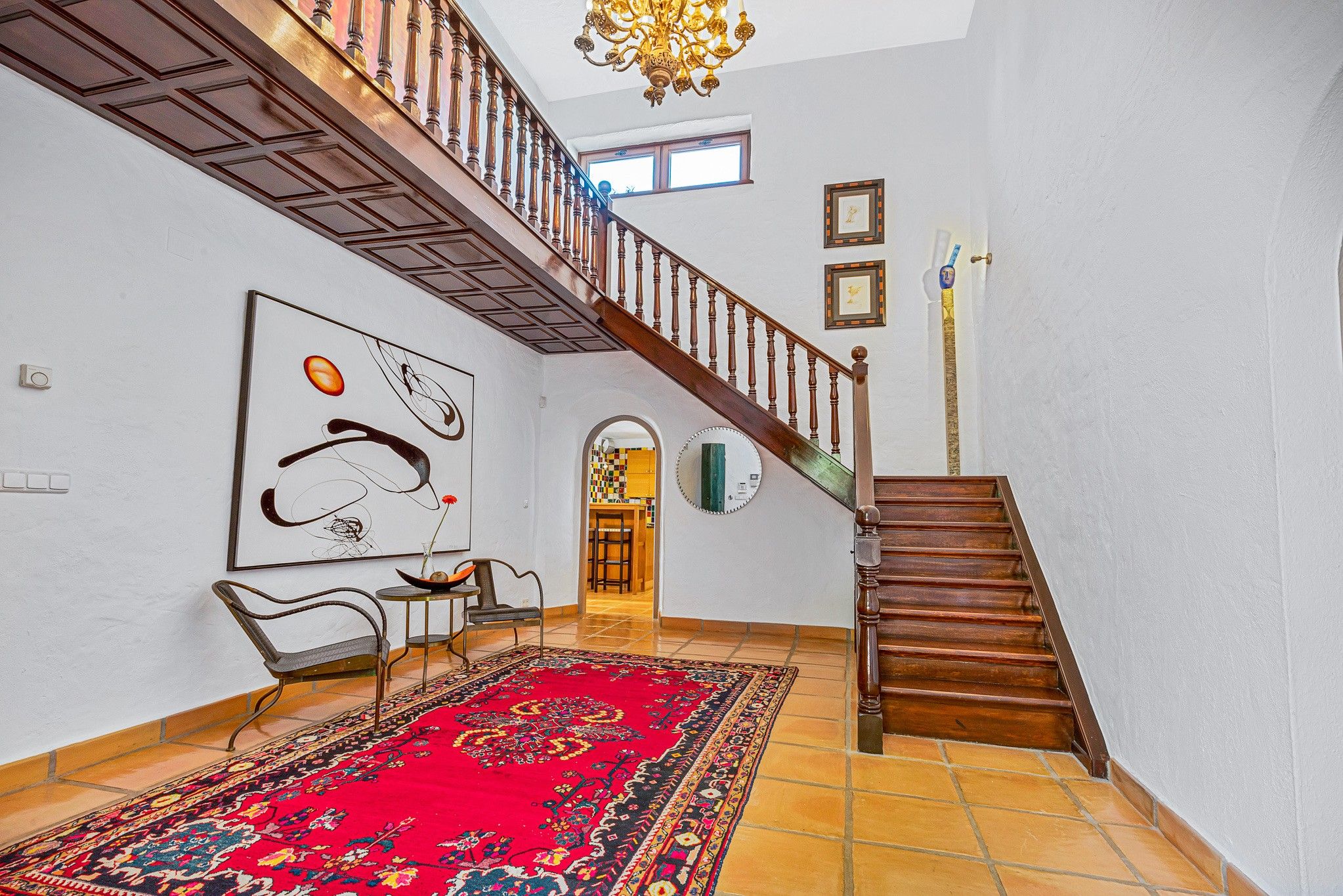 Un interior espacioso con una escalera, un tapete grande y un comedor.