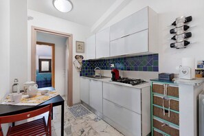 A compact kitchen with white cabinets, a gas stove, a sink, and a tiled backsplash. - Room 'Hope' with Shared Garden, Wi-Fi and Air Conditioning (Roma)