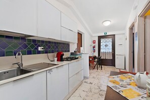 A compact kitchen with a sink, stove, and a tiled backsplash. - Room 'Hope' with Shared Garden, Wi-Fi and Air Conditioning (Roma)