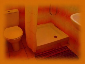 Ein kleines Badezimmer mit Toilette, einer Duschkabine und einer Badewanne.