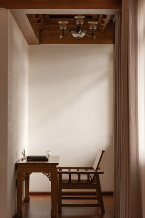 Quarto com uma mesa de madeira, uma cadeira e um lustre.